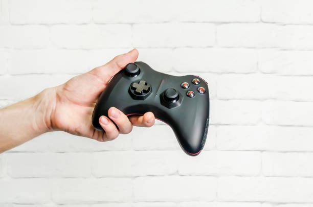 istock man holds wireless game controller in hand, gamepad for videogames. Hand demonstrates gamepad 1456772188