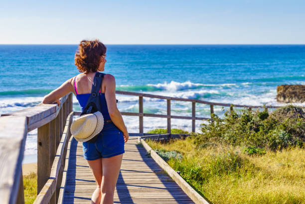 istock Woman walking on wooden path on sea shore 1456772443