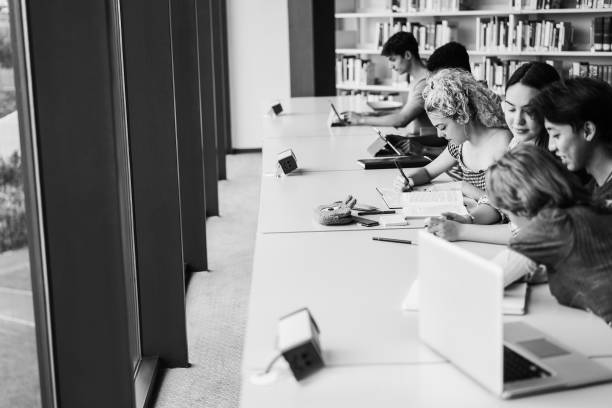 Young multiethnic group of students studying inside university library - Focus on blond girl face - Black and white editing