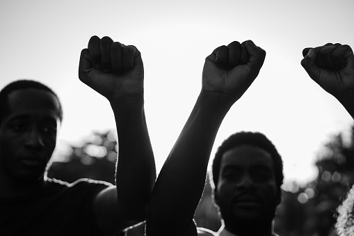 Black demonstrator people holding hands against racism - Focus on fists - Black and white editing