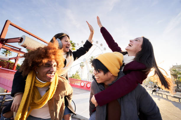 istock Cheerful two couple walking outdoors in a theme park and having fun celebrating high five 1456776788