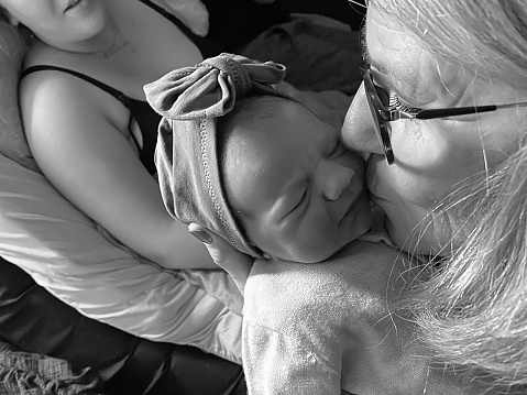 Just born baby in the arms of grandmother an mother in perspective
