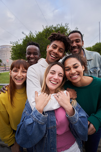 istock Vertical. Young people embrace looking at the camera outside. Smiling friends millennial generation. 1456777330