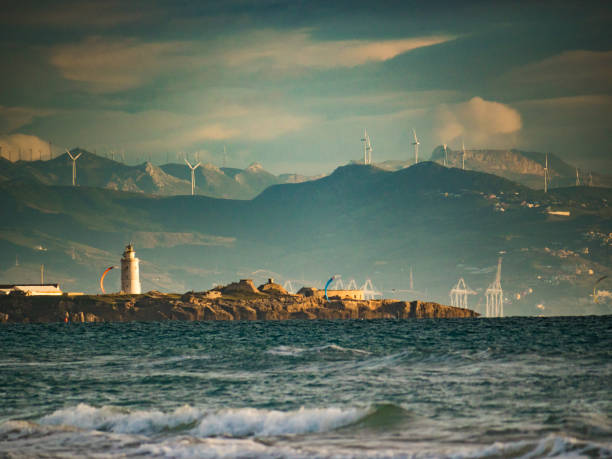 Coast landscape with Tarifa town on skyline and wind turbines in mountains. Costa de la Luz, province of Cadiz, Andalusia in Spain.