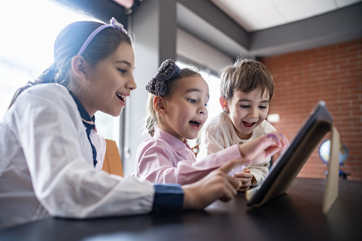 Children Playing Video Game Using Digital Tablet At Home