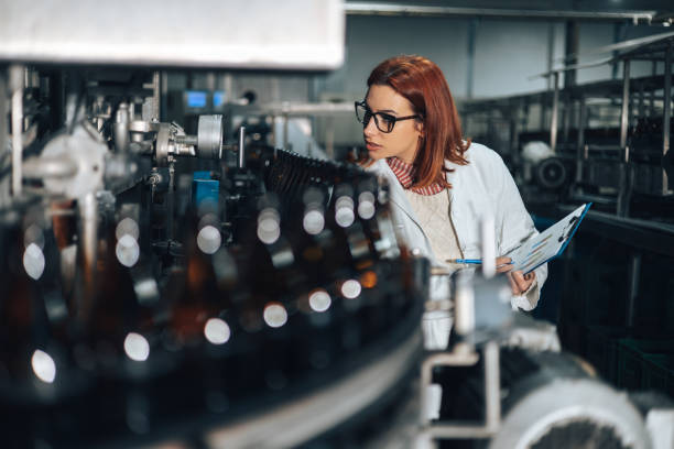 Beer Bottling Factory One young female worker doing quality check control in traditional beer bottling plant. bakers yeast stock pictures, royalty-free photos & images