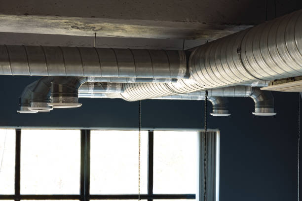 Silver ventilation pipes hanging from the ceiling inside the building stock photo