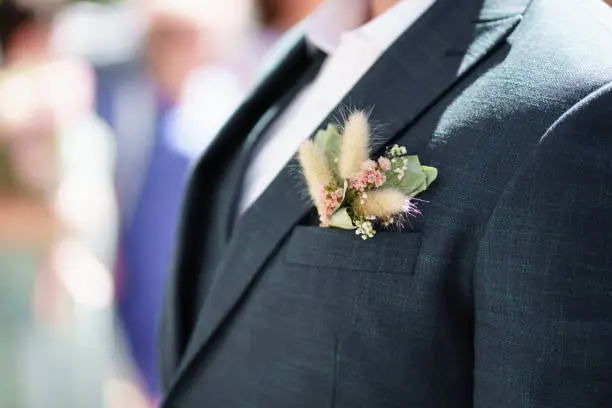 a dried flower boutonniere in the pocket of a man's jacket. a traditional decoration of the groom's wedding costume.