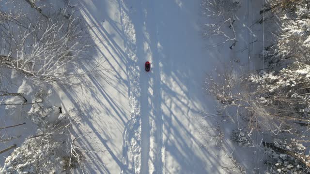 Aerial View of a Child Sledding Outdoors on the Snow in Winter at Sunset in Quebec, Canada