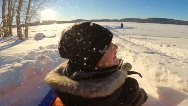 POV of Father and Son Sledding Outdoors on the Snow in Winter at Sunset in Quebec, Canada