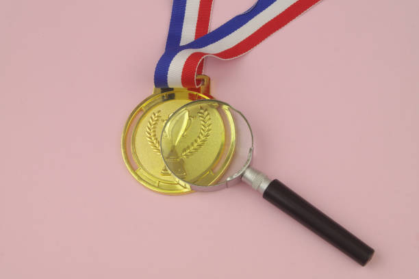 istock Gold medal and magnifying glass on pink. 1456793882