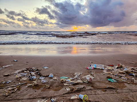Full frame shot of heap dirty plastic waste lying on the ground covering the sand of Kuta beach in Bali during sunset.