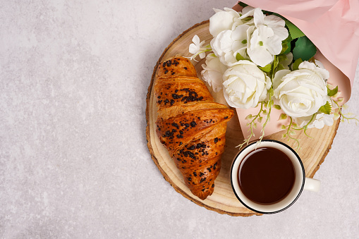 croissant, coffee, flowers on the wood on gray concrete background