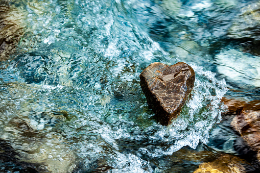 Stone heart in sparkling running water