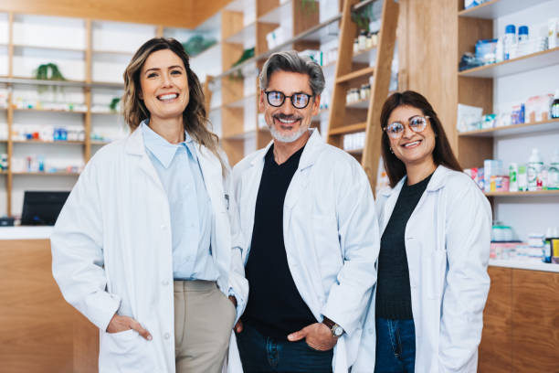 gruppo di farmacisti in piedi insieme in una farmacia - healthcare and medicine smiling group of people lab coat foto e immagini stock