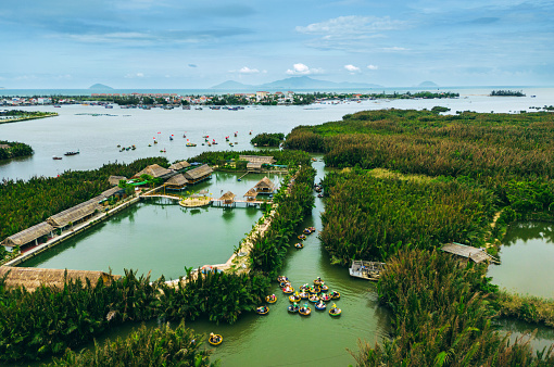Aerial view on tourists going on colorful round boat tour on lagoon in palm forest\nfamous destination near Hoi An ancient, Vietnam