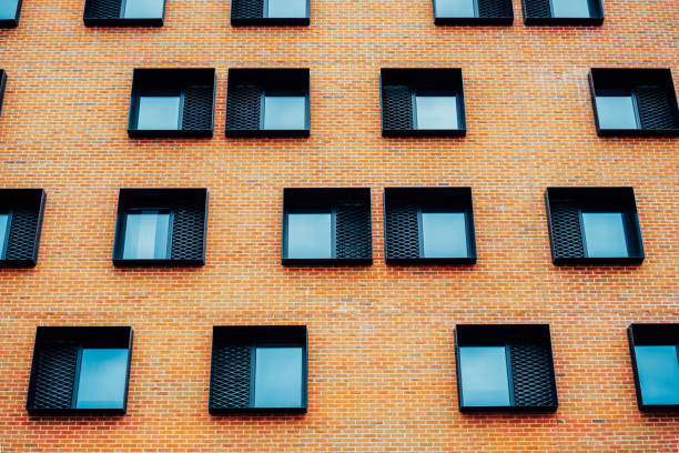 istock Many same quadratic windows on a modern brown brick building in daylight. Architecture concept. Strange window arrangement. Selective focus. 1456806070