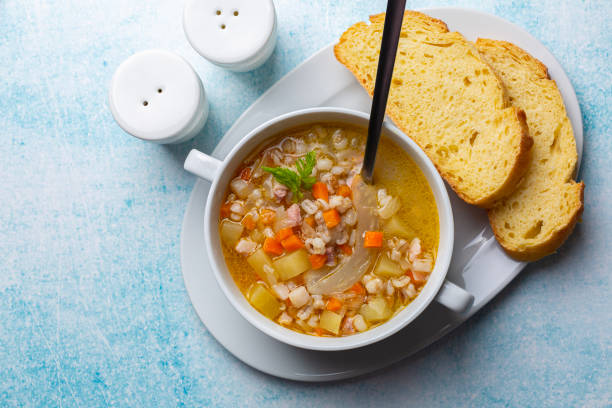 istock South Tyrolean barley soup Gerstsuppe, Graupensuppe, made with smoked pancetta or bacon, calery, fennel, potato, onion. Fresh bread.  Or Zuppa d'orzo. Light blue table surface. 1456806214