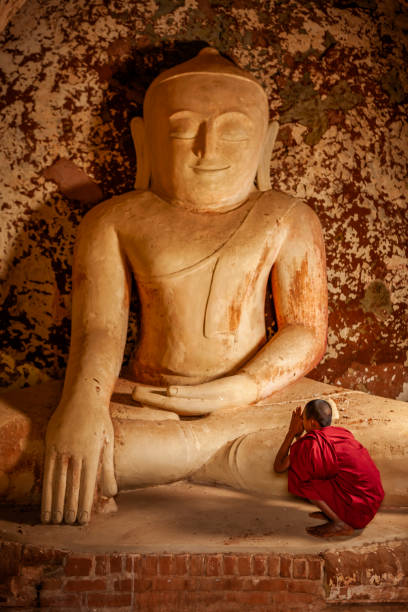 Two young buddhist monks praying inside an ancient temple, Bagan, Myanamar