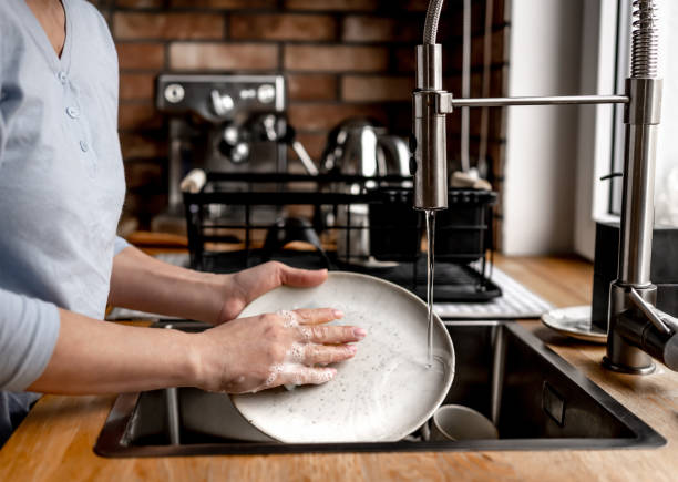 istock Girl washing dishes at kitchen at home 1456810133