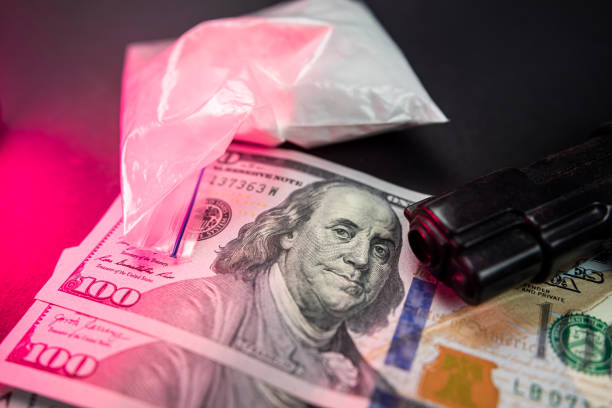 de la cocaïne dans des sacs à côté de dollars et un pistolet isolé sur fond noir. - narcotic gun medicine currency photos et images de collection