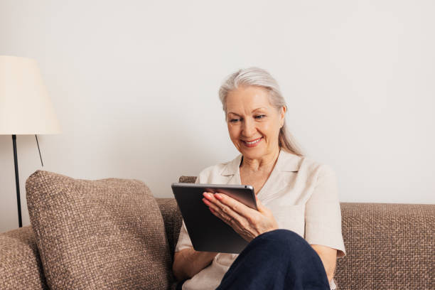 istock Aged woman with grey hair using a digital tablet at home 1456811961