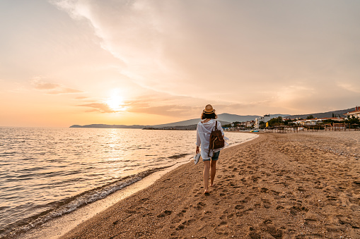 Beautiful young woman walking on the beach in Thasos, Greece as the sun sets.