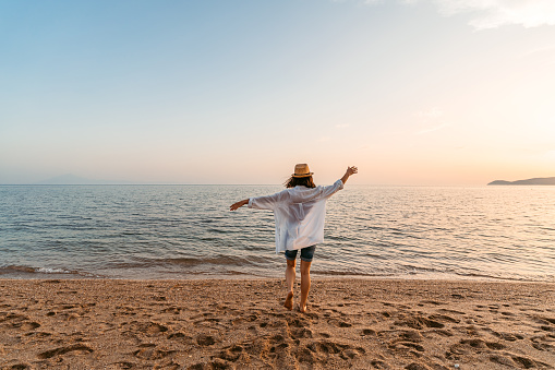 Beautiful young woman running on the beach in Thasos, Greece as the sun sets.