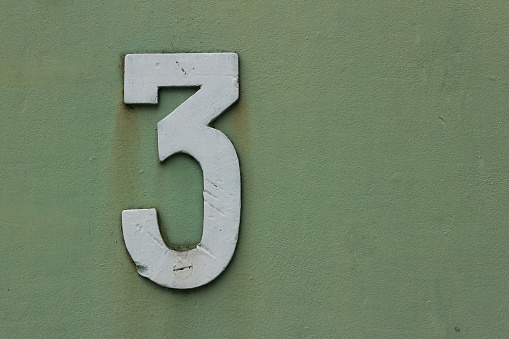 White number three on a grey-green background with blank space on the front side.