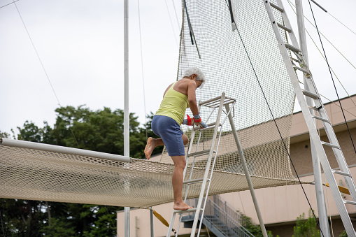 Mature trapeze artist descending the ladder after flying in the sky