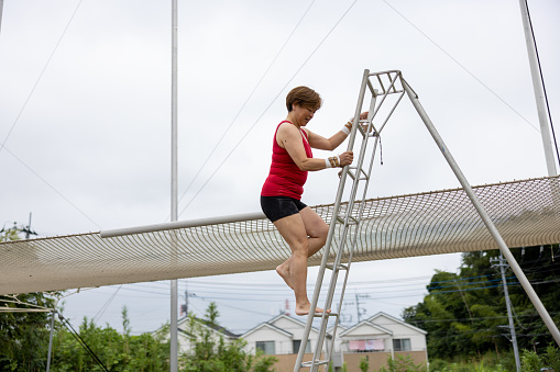 Mature trapeze artist descending the ladder after flying in the sky