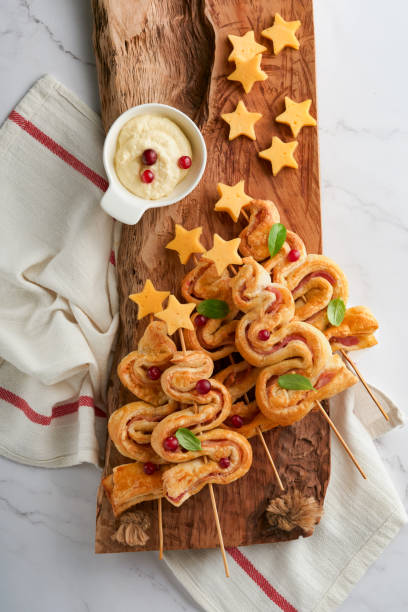 istock Christmas or New Year appetizer. Christmas tree shape puff pastry buns with cheese and ham. Group of Christmas tree shapes on wooden board. Festive idea for Christmas or New Year dinner. Top view. 1456817610