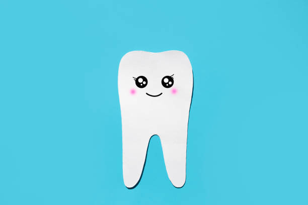 istock Silhouette of a healthy white tooth with a funny muzzle on a blue background. Flat lay, space for text. Children's tooth treatment concept. 1456820428