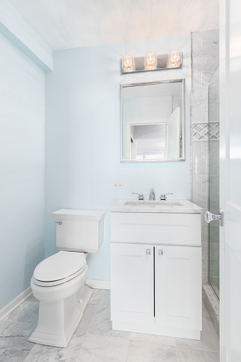 A small bathroom with blue walls, white vanity, and marble countertop.