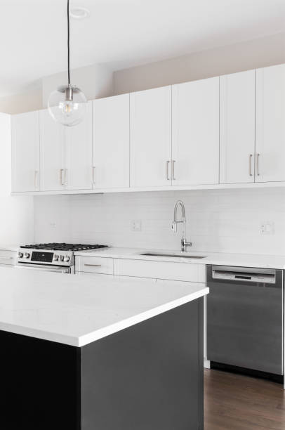 istock A modern kitchen with white cabinets, black island, and stainless steel appliances. 1456821900