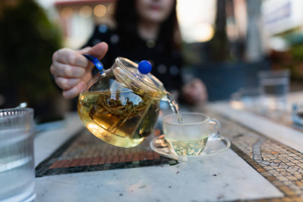 Woman filling cup with hot tea stock photo