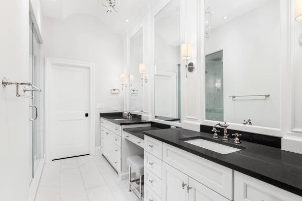 istock A large bathroom with white cabinets, black countertop, and walk-in shower. 1456822683