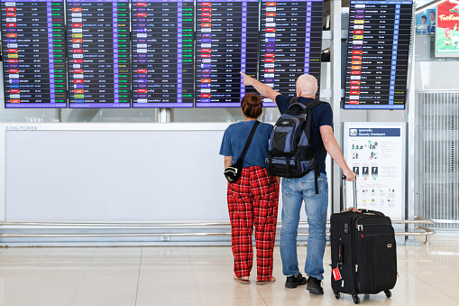 Bangkok, Thailand - January 16, 2023 :  traveler passengers with luggage looking at departure timetable board to checking flight at suvarnabhumi airport thailand. transportation and travel concept