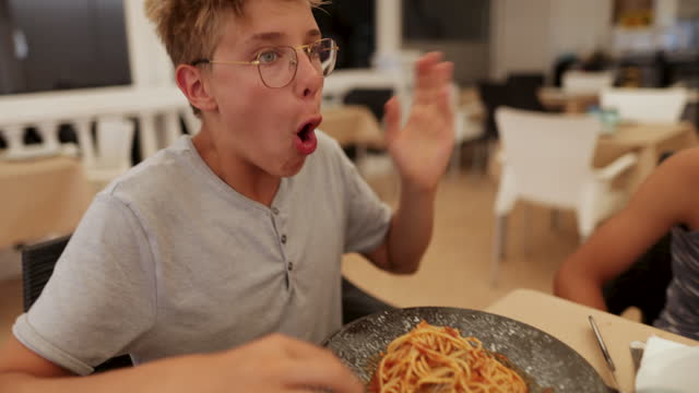 Teenage boy eating too hot spaghetti