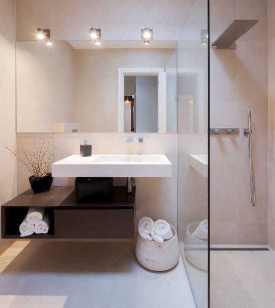 istock Modern bathroom front view with large light marble slabs. There are two sinks with a large mirror illuminated by spotlights 1456823003