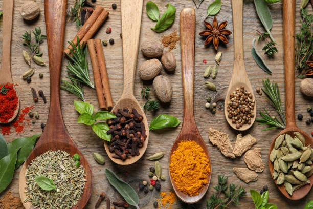 istock Different herbs and spices with spoons on wooden table, flat lay 1456823124
