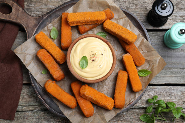 istock Delicious chicken nuggets and cheese sauce with basil on wooden table, flat lay 1456823951