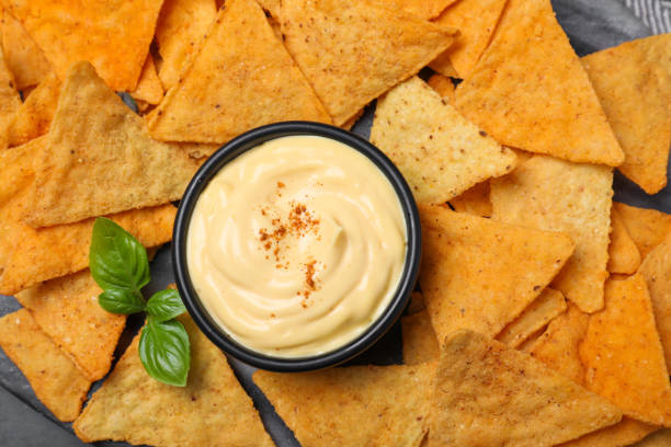 istock Delicious nachos and cheese sauce with basil on board, top view 1456825007