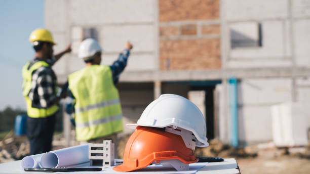 structural engineer and architect working with blueprints discuss at the outdoors construction site. - hoofddeksel stockfoto's en -beelden