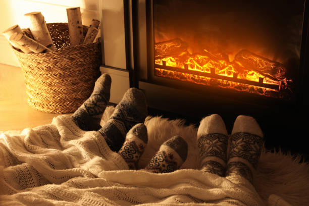 famille en chaussettes chaudes reposant près d’une cheminée à la maison, gros plan des jambes - blanket fireplace winter women photos et images de collection