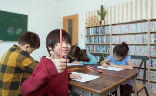 Young girls and boys performing tasks in school together, writing in copybook.