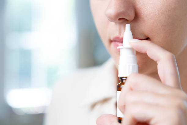 Close-up shot of sick young woman using nasal spray stock photo