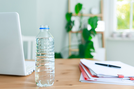 A bottle of water standing on the desk. The importance of drinking water during the day
