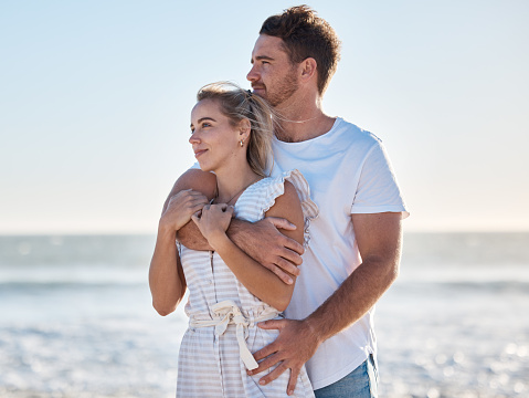 Love, hug and happy couple at beach, travel holiday and anniversary, honeymoon and enjoy Hawaii together in summer. Young man, woman and vacation at ocean, sea and happiness, support and care outdoor