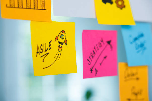 the word agile and rocket symbol on a yellow adhesive note - agilidade imagens e fotografias de stock